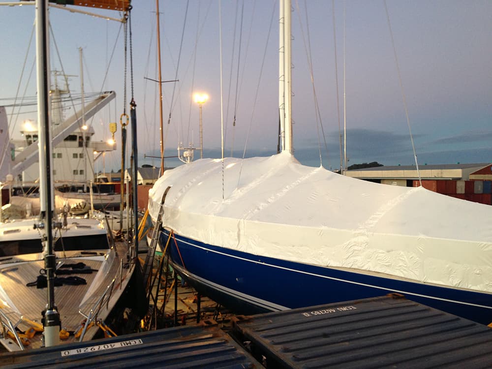 Shrinkwrapped yacht undergoing maintenance at a shipyard in Auckland