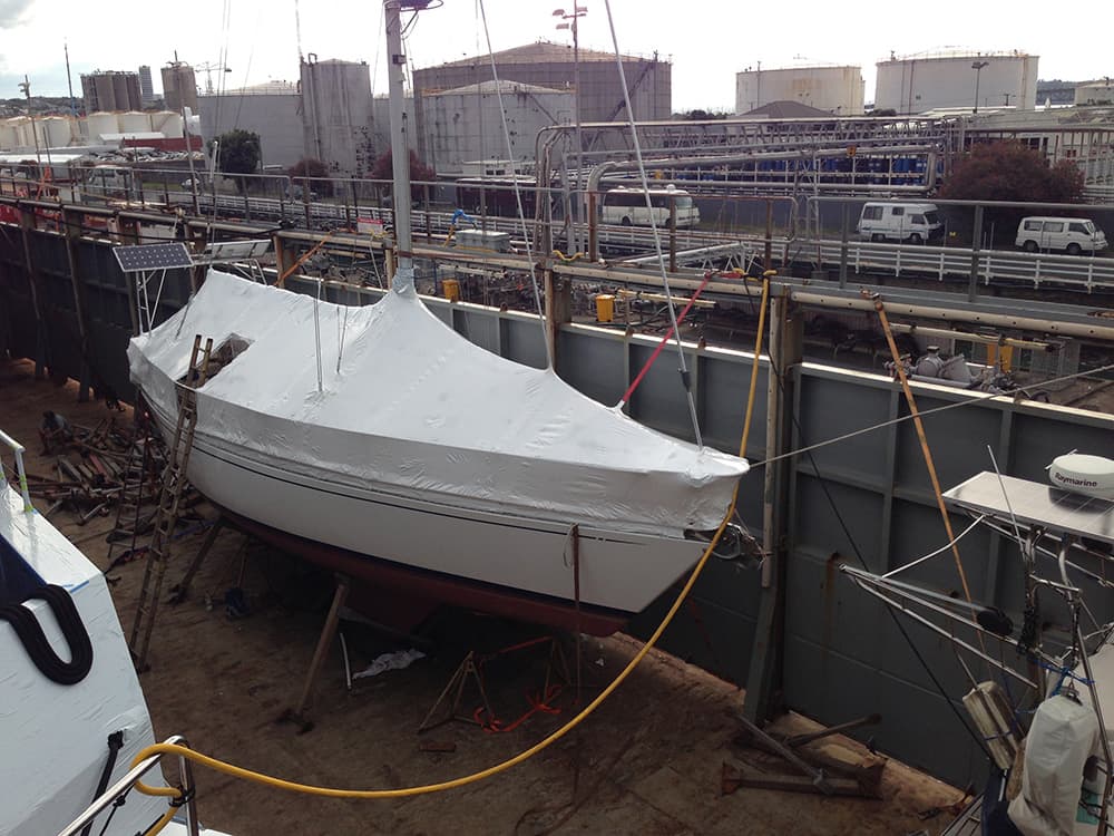 Shrinkwrapped yacht undergoing maintenance at a shipyard in Auckland